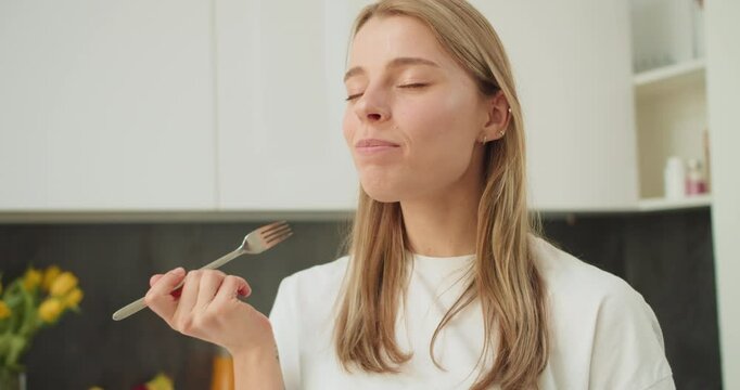 A young woman savoring a bite of mozzarella in a modern kitchen, enjoying the simplicity and freshness of a healthy meal