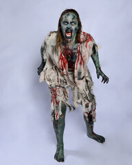 portrait of scary female model wearing spooky halloween costume wearing, ripped clothes and fake...