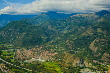 Obraz premium Panoramic landscape of the Italian city, photos from a drone, quadcopter, aerial photography. The city, the houses with tiled roofs, the road and the mountains. Layout. A miniature. View of Piedmont, 