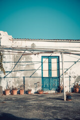 Close up shot of a petrol blue door or teal colored entrance or front door with a golden handle in a mediterranean island. Summer vibes, italian style, aeolian tourism.