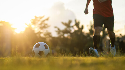 Action sport outdoors of boy having fun playing soccer football for exercise in community rural area under the twilight sunset sky. 