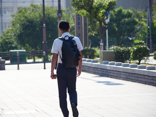 夏の朝の通勤時間で街を渡るひとりの男性サラリーマンの姿