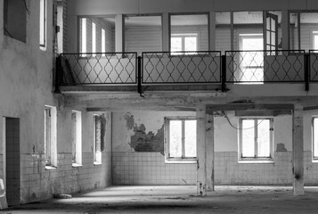 Silence and emptiness in this factory hall of an abandoned dairy factory. People used to work here and now there is silence. Photo is in black and white so the pillars and windows are clearly visible