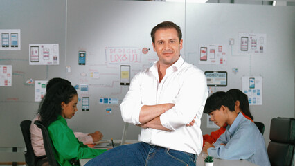 Obraz premium Portrait of professional businessman with arm crossed standing and looking at camera. Successful business people smiling to camera while business group discussion about marketing plan. Manipulator.