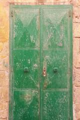 An old wooden green door in a Mediterranean setting in a historic town in Italien.