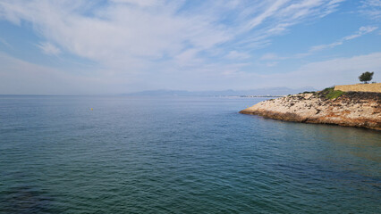 Fototapeta premium Balearic Sea, Salou, Spain. Beach, turquoise transparent sea, small waves. Landscape on the coast, rocks. Vacation at sea