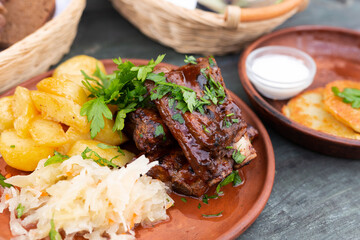 Bavarian pork ribs baked with sauce with boiled potatoes and sauerkraut