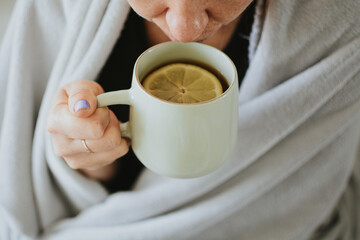 a woman drinks tea with lemon against the background of medicines for the treatment of seasonal cold