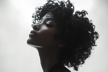 A black silhouette of an African American woman with curly hair, standing against a white background The figure is centered and in profile view, showcasing her graceful posture