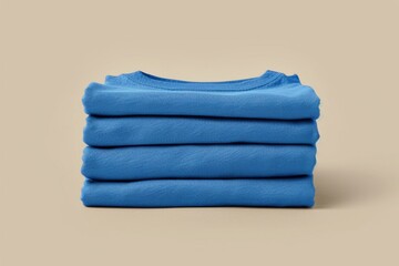 Fototapeta premium A stack of blue folded shirts on a beige background, suitable for fashion, storage or commercial use