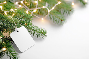 Festive Christmas tree branches adorned with lights and a blank gift tag for holiday celebrations