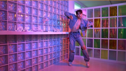 Close up of asian performer with sun glasses moving freestyle dance while looking at camera at nightclub. Happy street dancer dancing and show footstep with colorful bright neon light. Regalement.