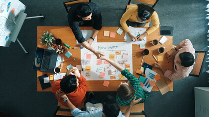 Top down aerial view of professional business people hands making scrum task board to manage workflow in workplace. Diverse smart team shaking hand and making agreement at meeting room. Convocation.
