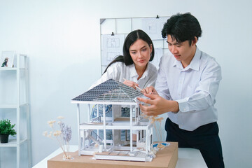 Portrait of cooperative engineer team working together to measure house model by using ruler and...