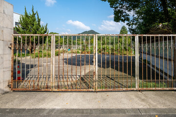 A weathered metal gate with hints of rust guards the empty yard of an old state-owned company in China. A sense of abandonment, signs of neglect, and a glimpse into the past.