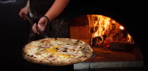 the chef took the finished pizza out of the Neapolitan wood-fired oven