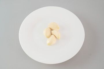 A bunch of garlic cloves are spread out on a white background