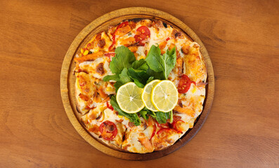 Mediterranean style salmon fish pizza  topped wih rocket leaves and lemon slices