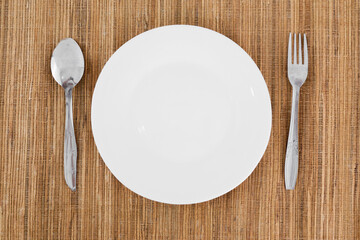 A white plate with a fork and spoon on a table