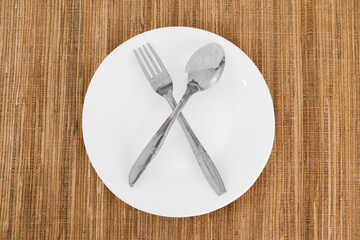 A white plate with a fork and spoon on a table