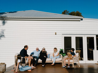 Multigeneration family sitting outside the wooden deck in the garden.