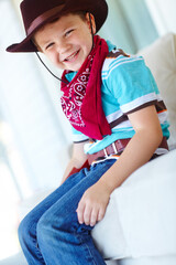 Obraz premium Portrait, cowboy or child with smile in home, childhood and dress up for halloween concert in living room. House, happy kid and fantasy with fashion for character role, cosplay and confident in Texas