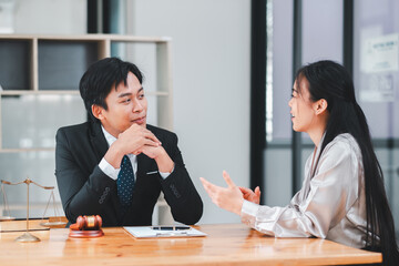 Two business professionals engaged in a discussion at a modern office desk with legal documents and a gavel.