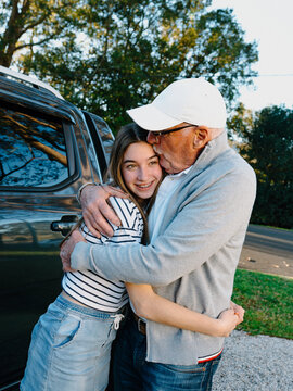 Grandfather embracing granddaughter outside the house.