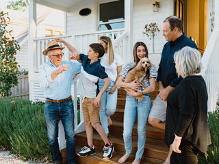 Multigeneration family standing on the steps in front of their house.