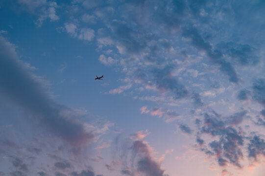Clouds in the dusk sky and a small-looking airplane.