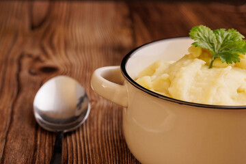 Freshly made mashed potatoes in a bowl with a spoon on a wooden table, detailed view of creamy and smooth mashed potatoes ready to serve