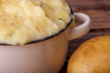 Delicious Mashed Potatoes with Raw Potatoes on an Aged Wooden Table