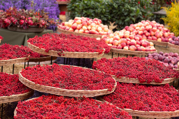 Horizontal photo. Red berries and apples on straw trays. Vegetable shop at street market. Autumn harvest festival Tbilisoba. Holiday fair. Tbilisi. Georgia. Showcase. Healthy food, eat. Berry, fruit