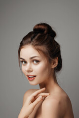 Naklejka premium Beautiful young woman with hands on face posing on gray background