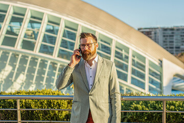 Portrait of young businessman telephoning with smartphone. Businessman with phone in an urban setting.