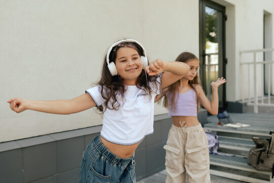 Happy funky gen Alpha girls hears her favorite music in headphones and dances to it. Part of a series