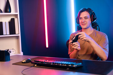 Enjoy smart gaming streamer with control joystick, playing game online of live streaming social media group with team skilled players on computer at modern technology cyber neon light room. Pecuniary.