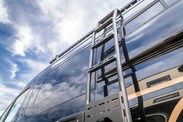 detail of a camper van with side windows, roof racks and a ladder