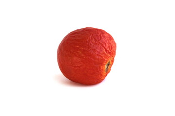 Spoiled product, wrinkled tomato lies on a white background.