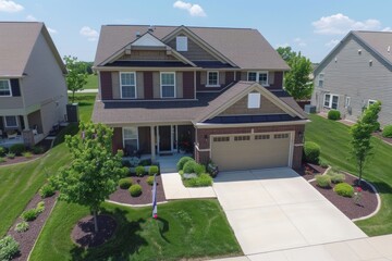 A two-story house with a brick exterior and a large driveway in a residential neighborhood.