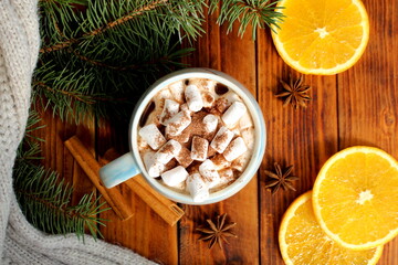 There is a mug of cocoa and marshmallows on the wooden table.