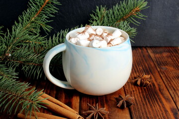 There is a mug of cocoa and marshmallows on the wooden table.