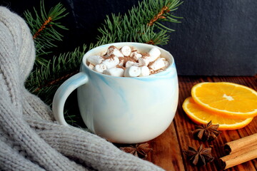 There is a mug of cocoa and marshmallows on the wooden table.