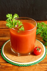 One glass with tomato juice stands on a wooden table.