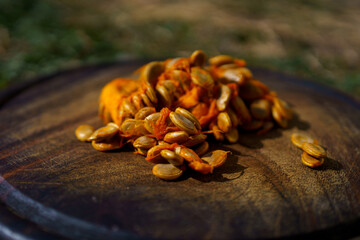 Raw pumpkin seeds on a wooden background, pear-shaped pumpkins lie nearby, autumn harvest