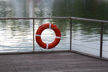 Obraz premium There is a lifebuoy hanging on the fence at the pier near the reservoir.