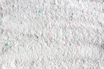 Texture of white washing powder with bright multi-colored specks.