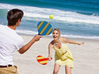 Friends, tennis and beach play by waves together for fun, holiday or bonding with sports and...