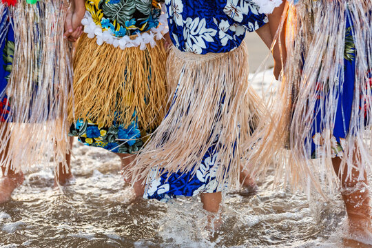 Torres Strait Islander children in traditional floral dresses and skirts standing together in ocean