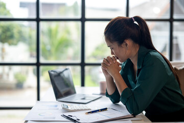A woman is sitting at a desk with a laptop and a calculator